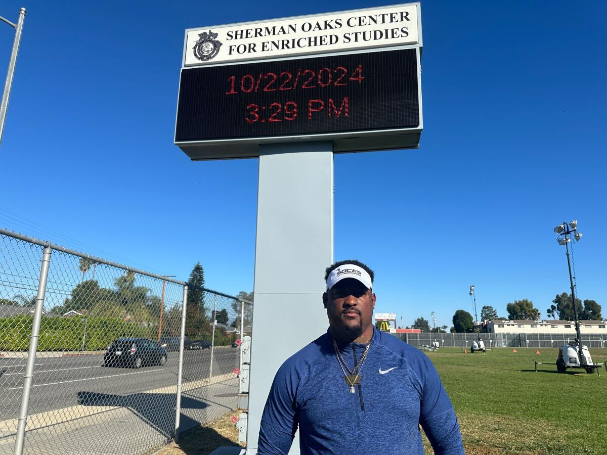 Sherman Oaks CES coach Dayvon Ross poses for a photo under a sign on campus.