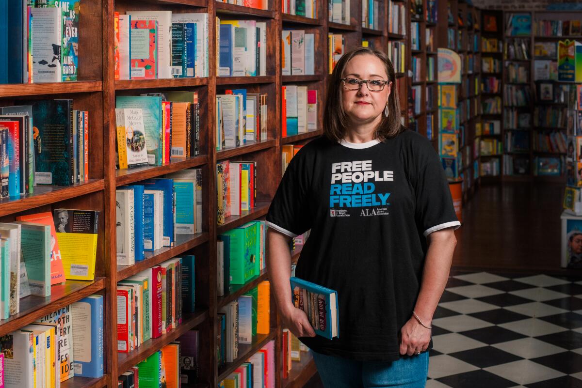 Amanda Jones stands next to library bookshelves and wears a shirt that says Free People Read Freely.