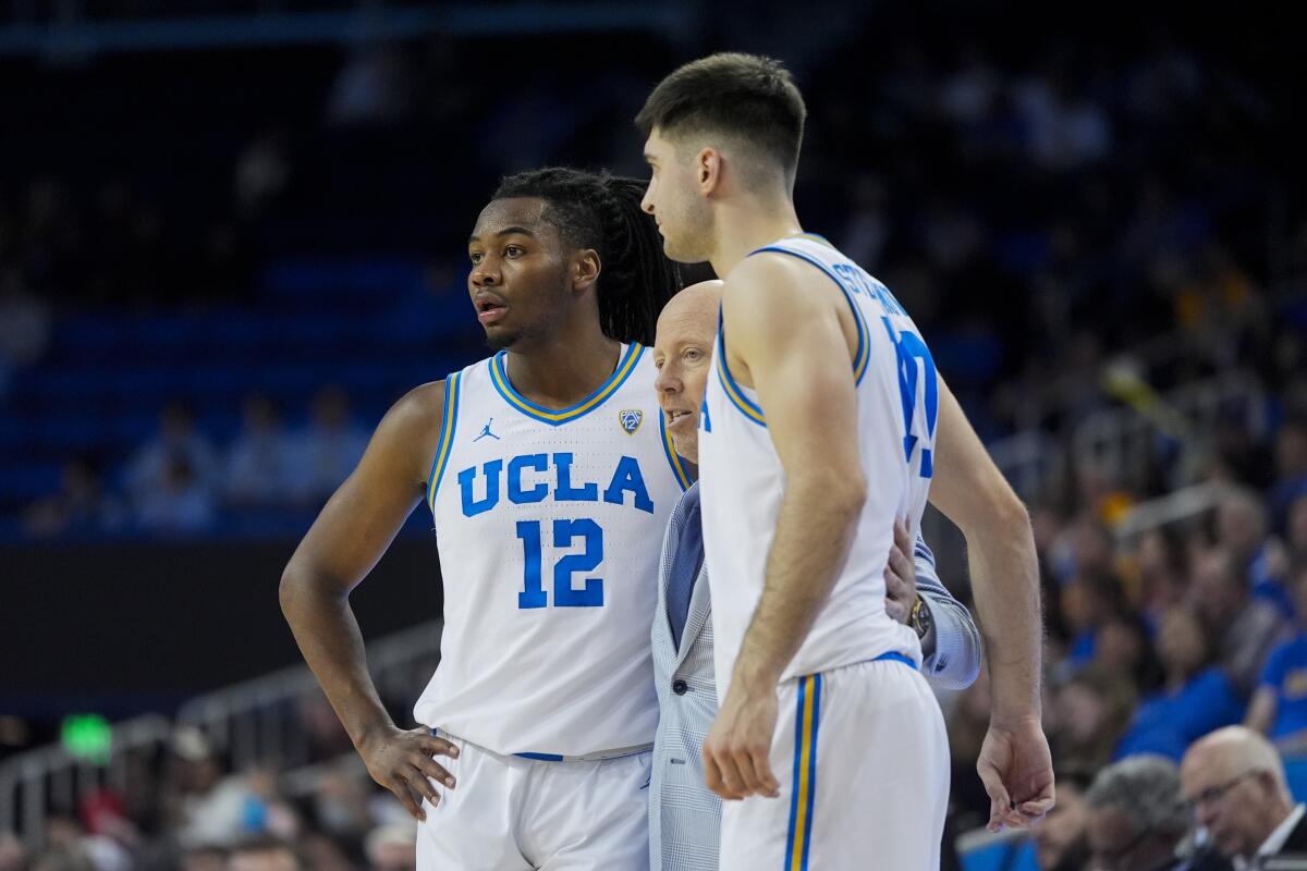 UCLA coach Mick Cronin, center, talks with guard Sebastian Mack (12) and forward Lazar Stefanovic (10) during a break in play