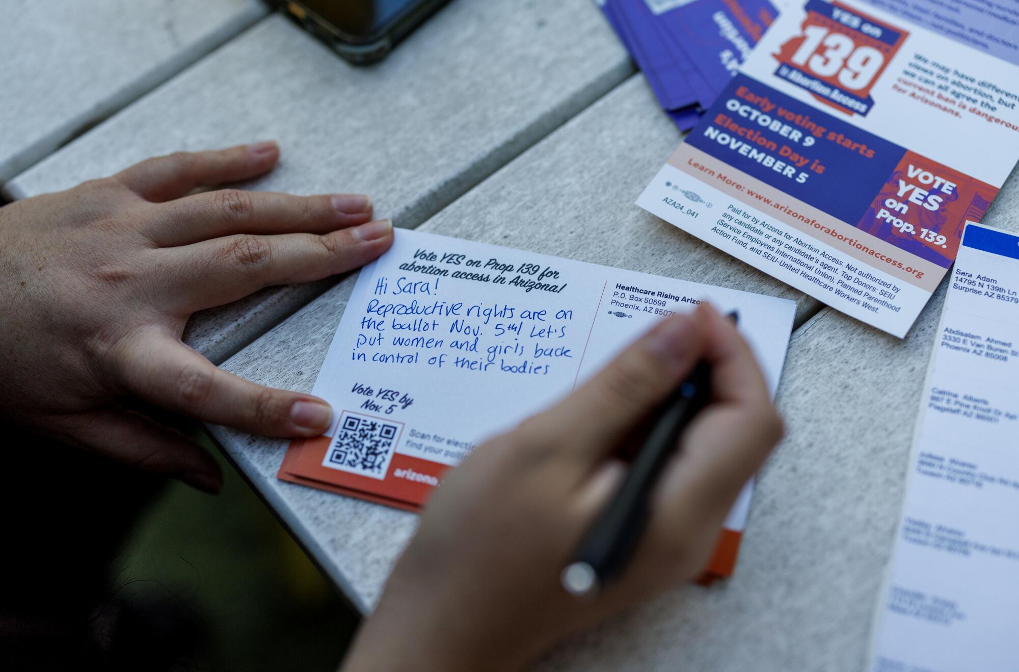 A closeup of hands writing a postcard