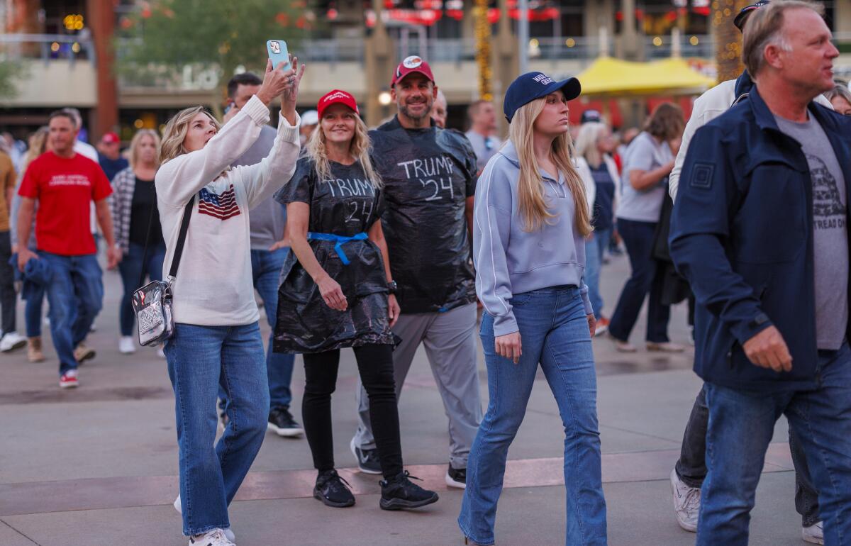 People wear red hats and garbage bags that say "Trump 24"