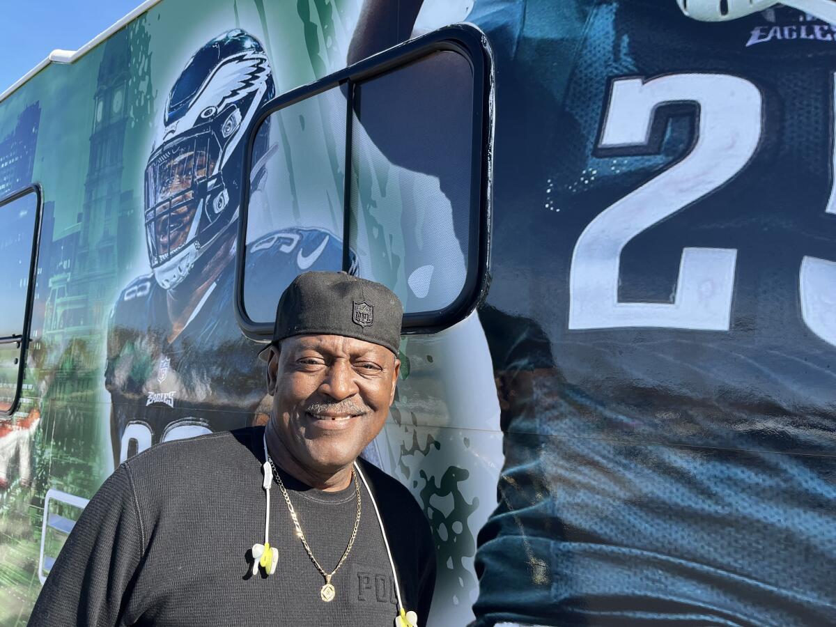 A man with headphones standing beside a painting of Eagles players on his van