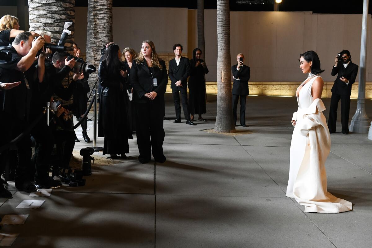 A woman in a long white gown pauses for photographers ag a gala.