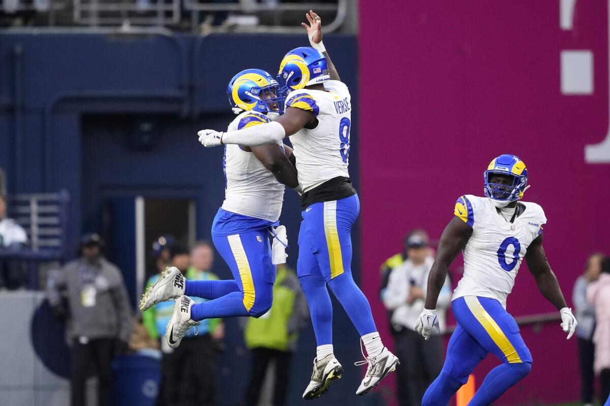 Rams Kobie Turner (left) and Jared Verse (8) celebrate a defensive stop against the Seahawks as Byron Young (0) watches.