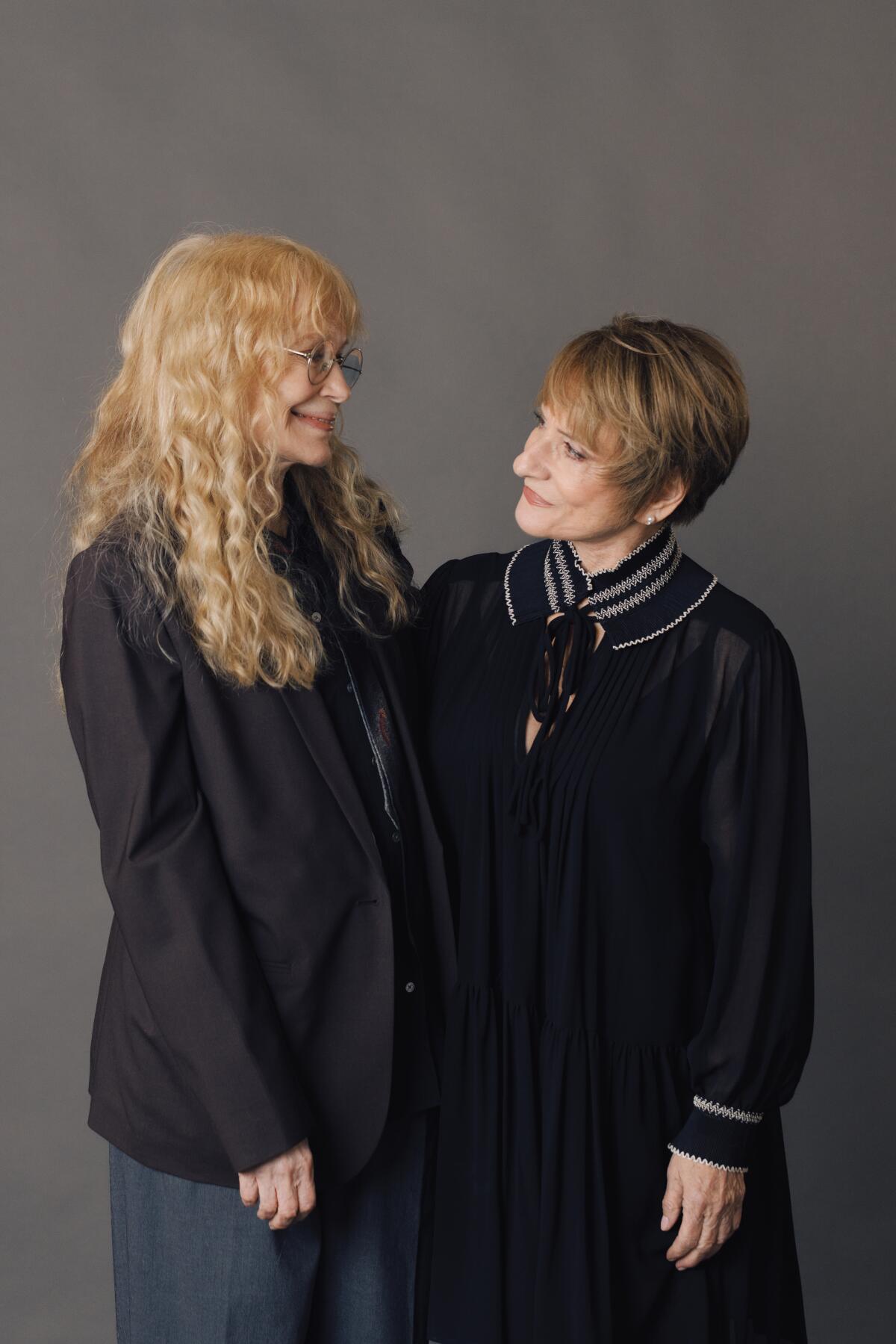 Mia Farrow and Patti LuPone stand side by side, smiling at each other