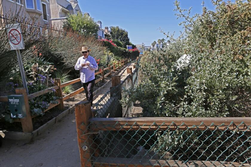 A fenced-off pathway leads to the trail entrance.