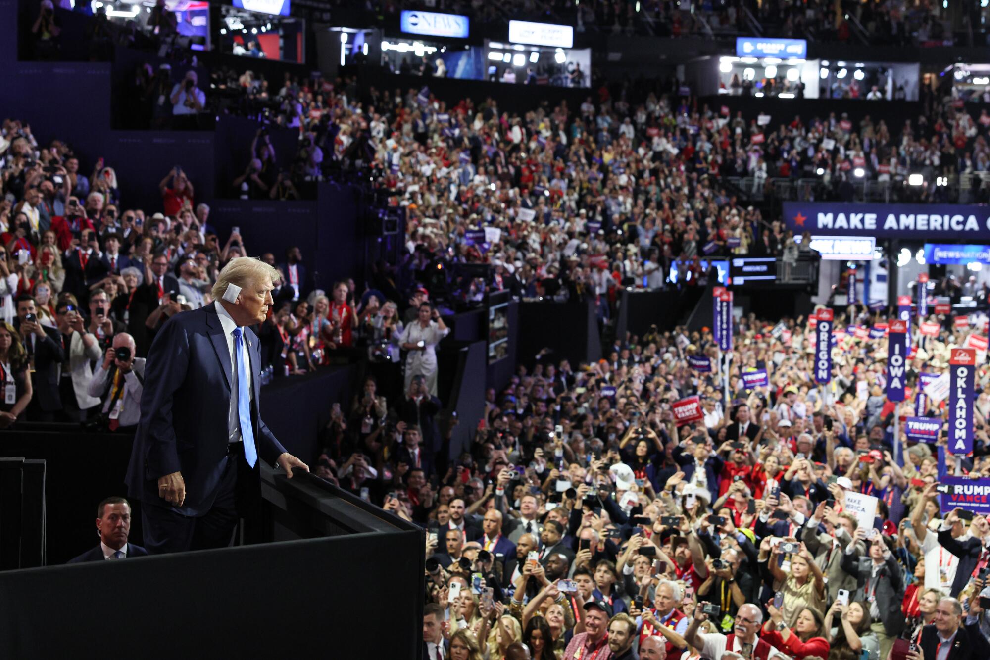  Donald Trump, with a bandaged ear, looks over a crowd 