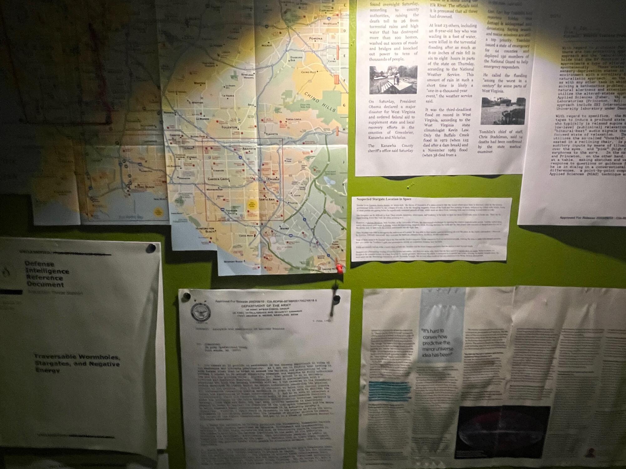 A wall with a map and various news stories and pamphlets. 