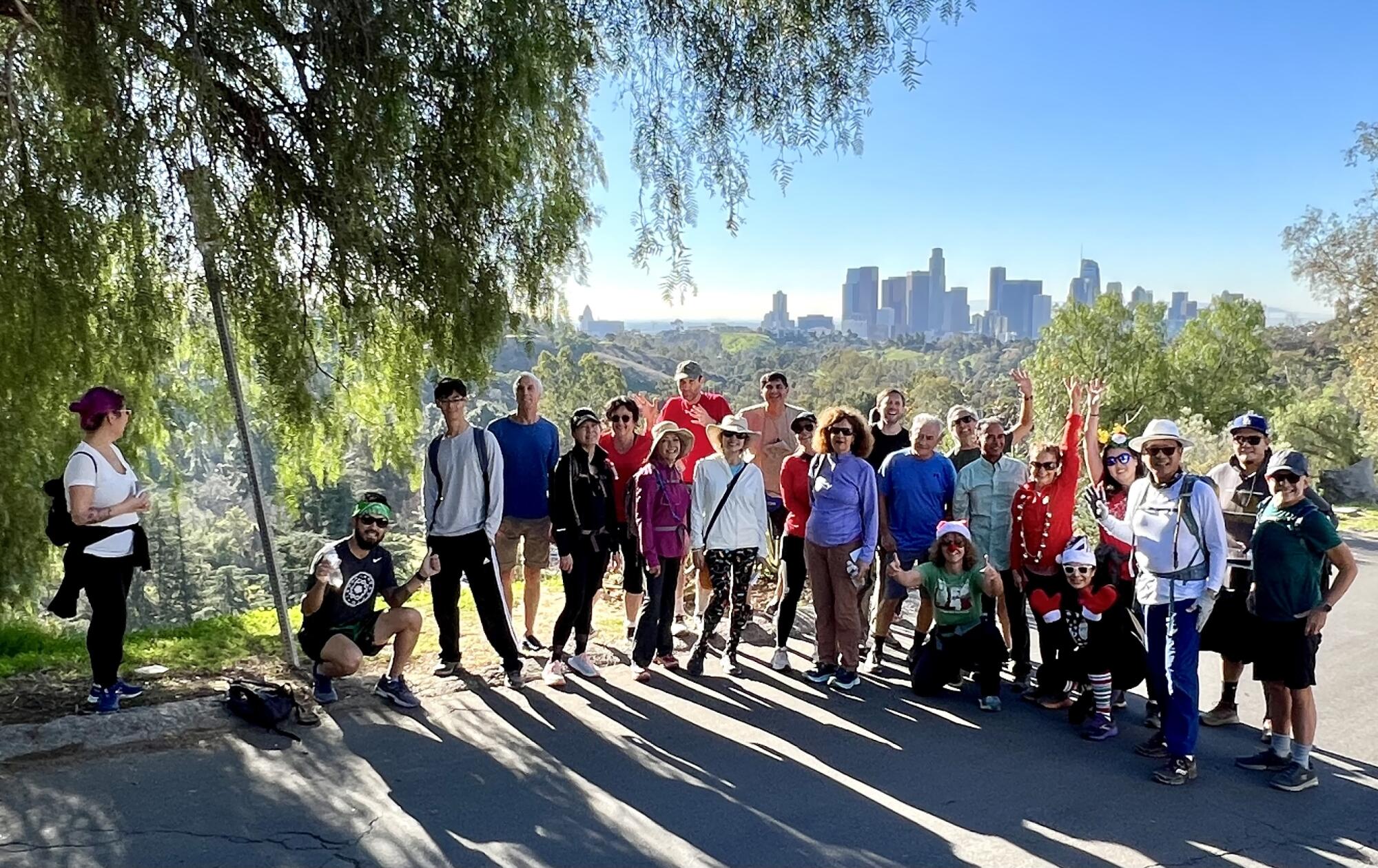 Los Angeles Hiking Group members rest under a tree, the downtown Los Angeles skyline visible behind them