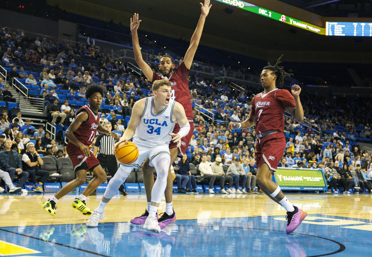 UCLA forward Tyler Bilodeau drives under the basket near two Rider players