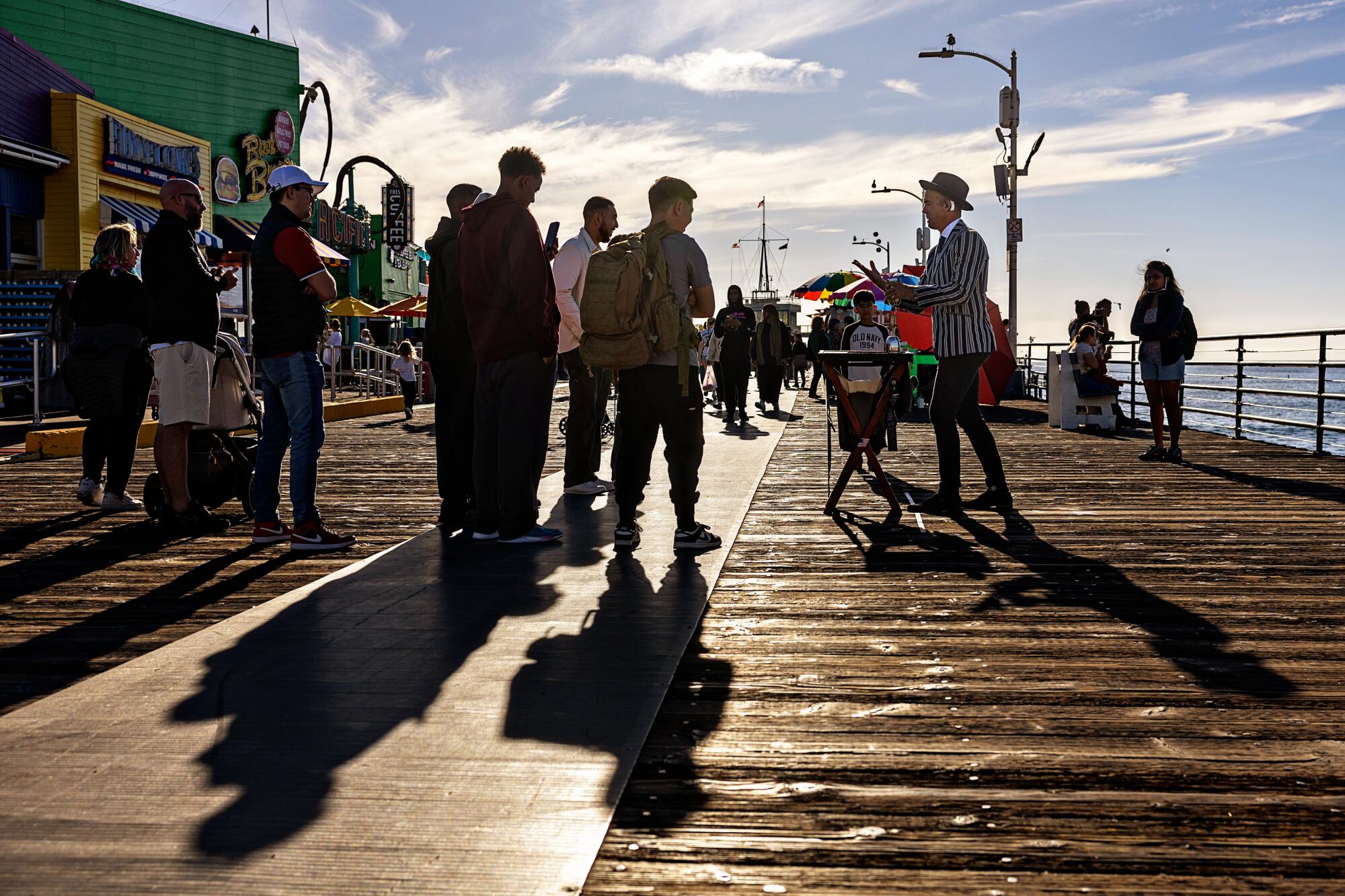 People are entertained by a magician as they enjoy a sunny day at the Santa Monica Pier.