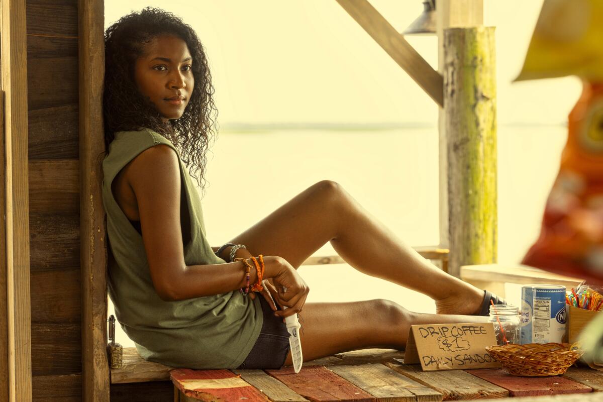 A woman sits on a porch overlooking the sea. 