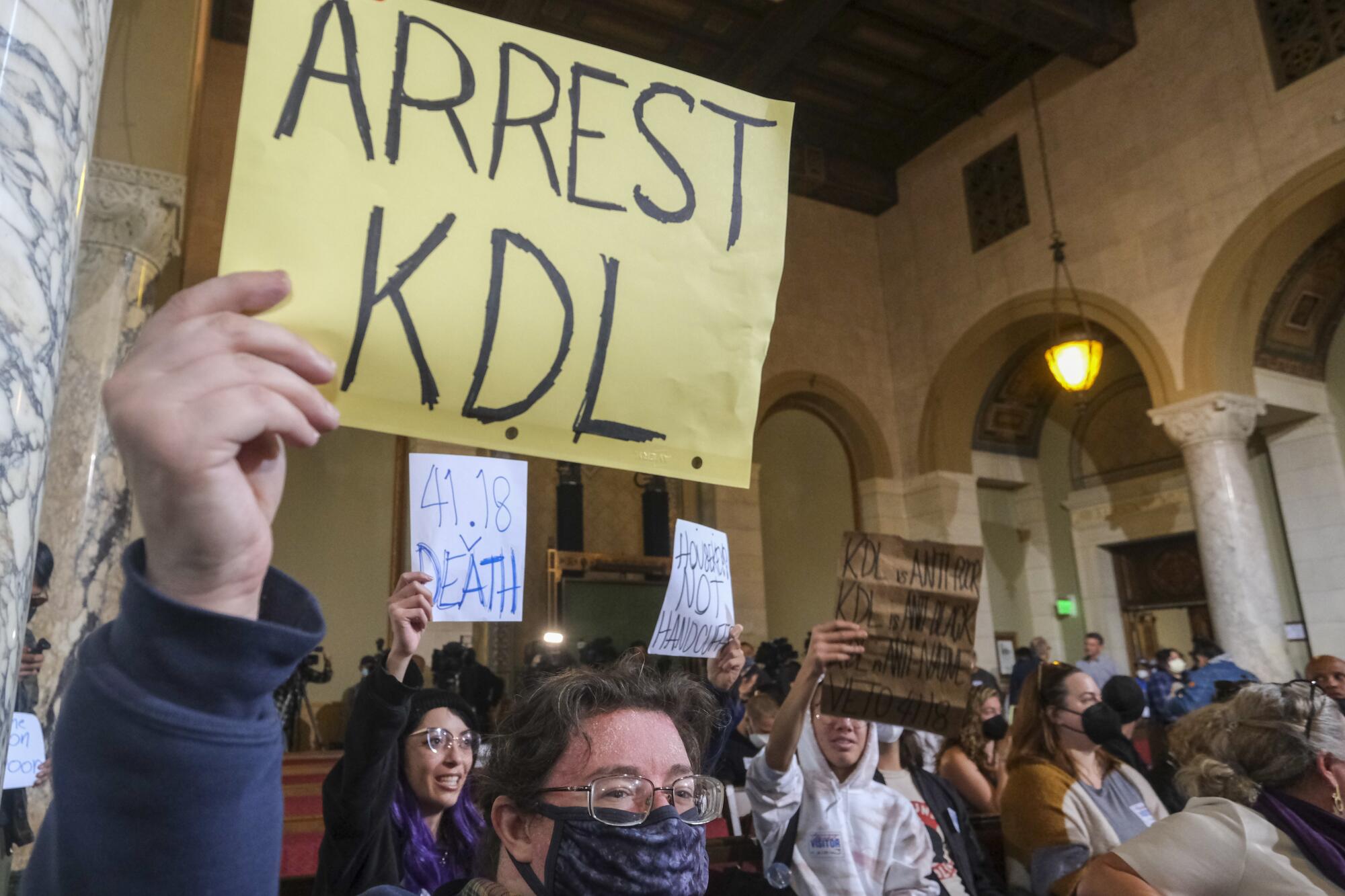 Protesters hold signs and shout slogans during the Los Angeles City Council meeting Tuesday, Dec. 13, 2022