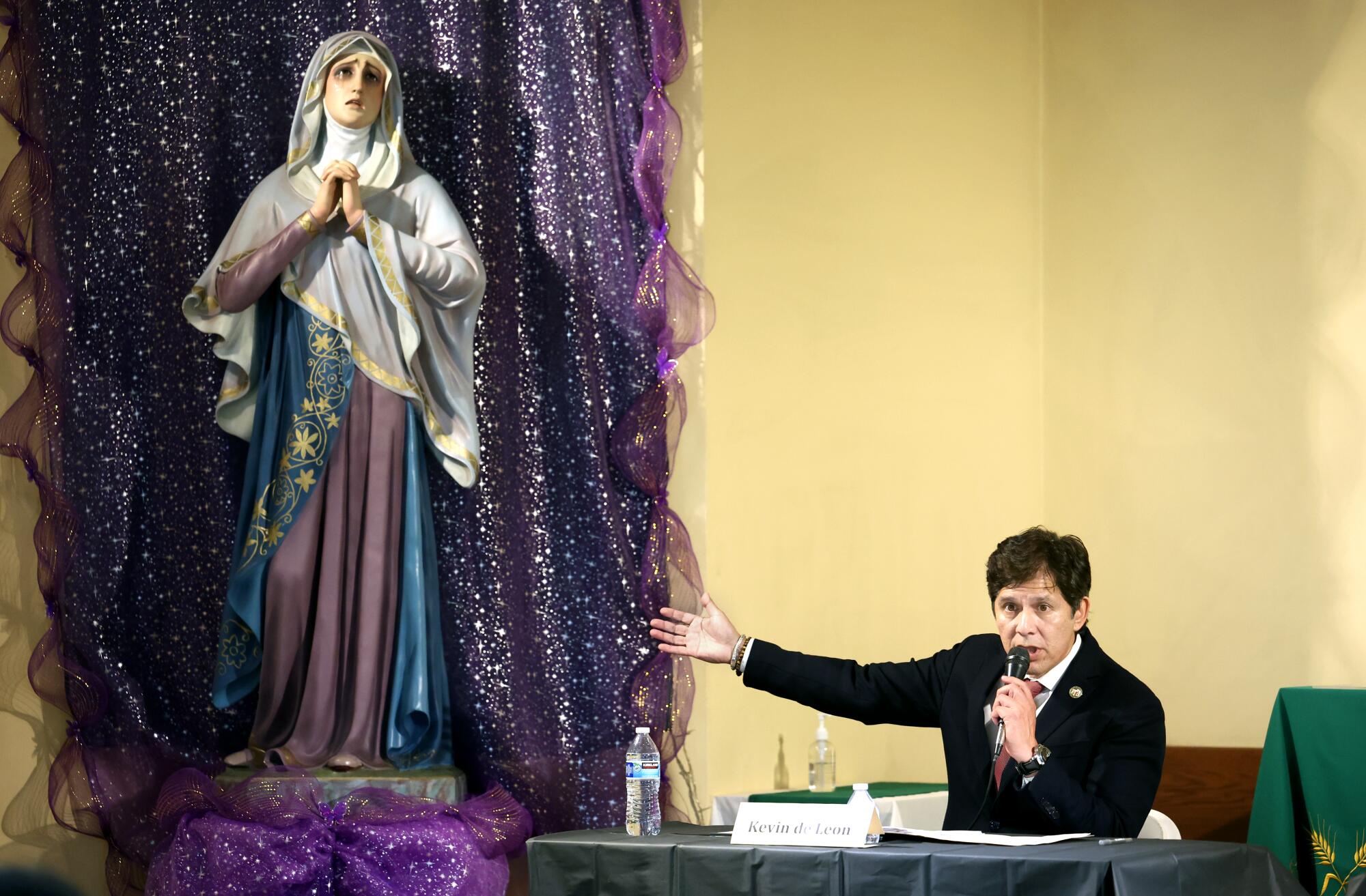 Kevin de León gesturing near a statue of Our Lady of Sorrows