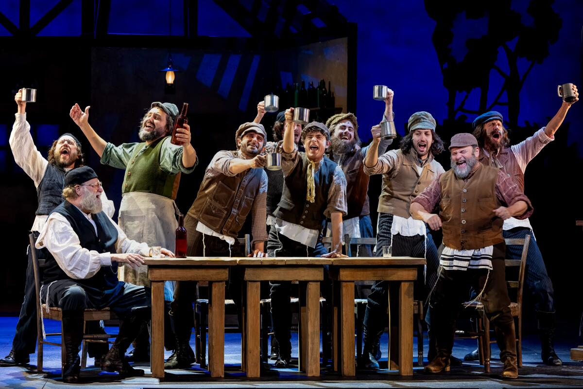 A group of men, mostly standing, lifting mugs in a toast