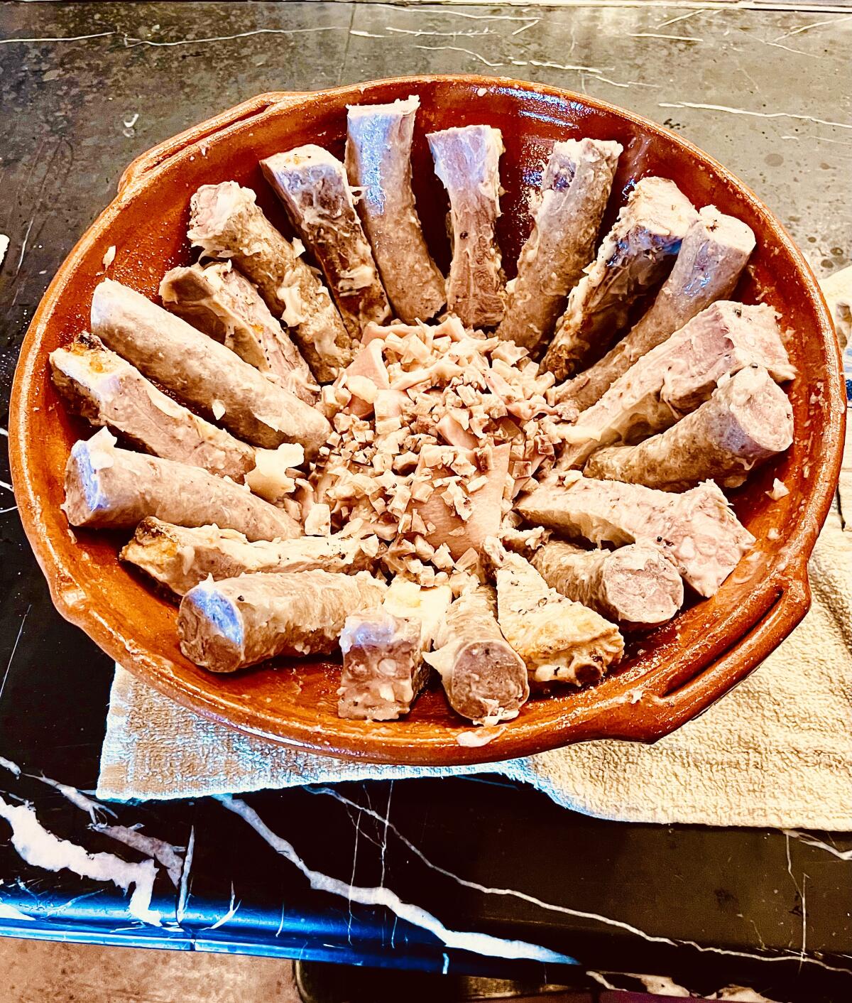 Pork ribs and sausage are arranged around the inside walls of a cassoulet pot.