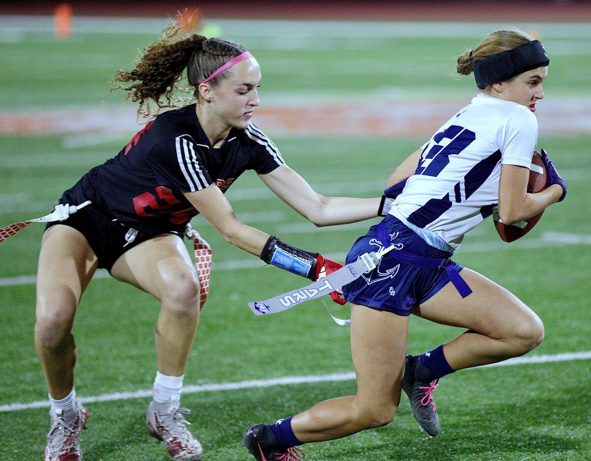 Orange Lutheran's Julia Oberholtzer pulls the flag of Newport Harbor's Skylie Cid on Saturday.