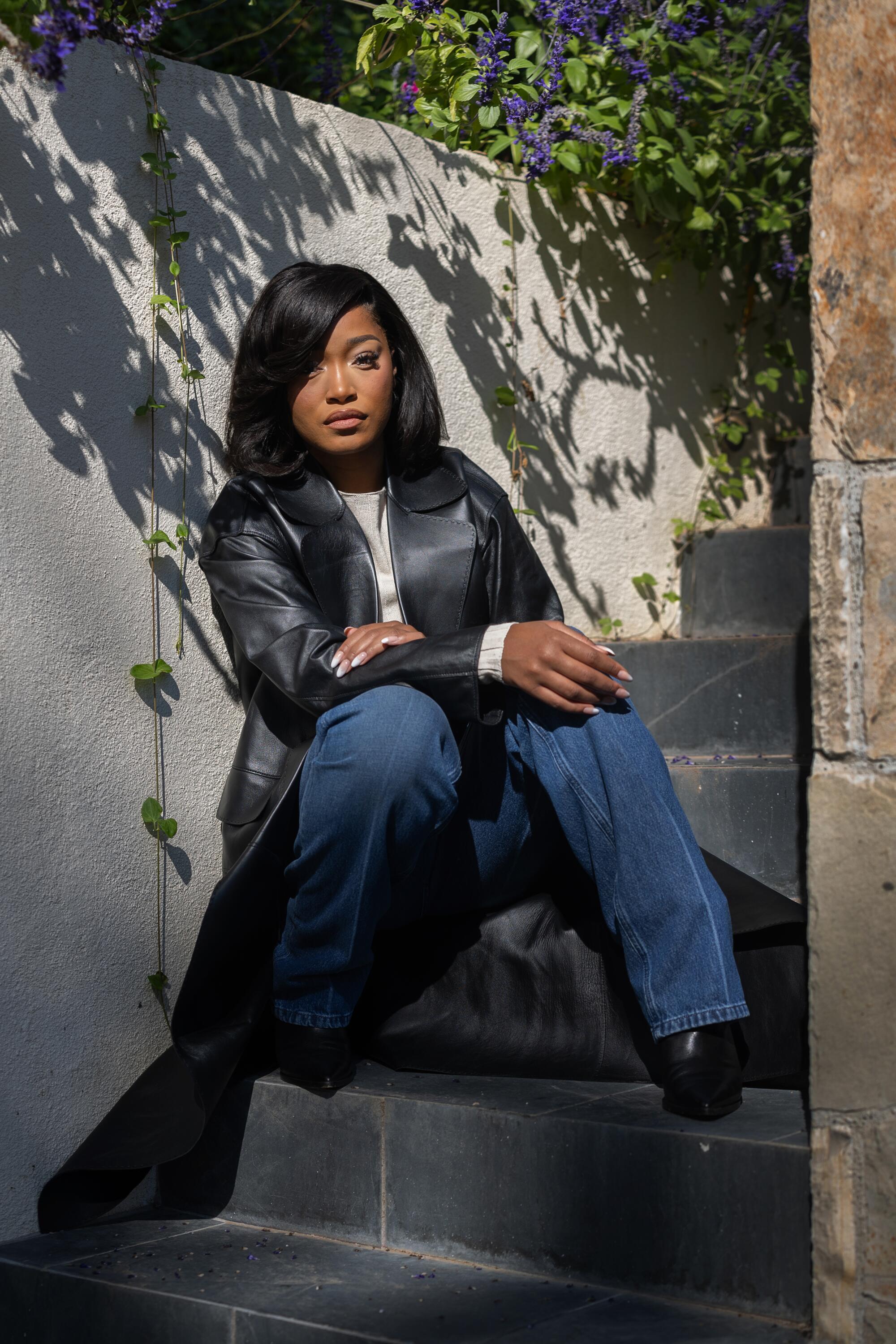 Keke Palmer sits on steps outdoors at her home in Encino. 