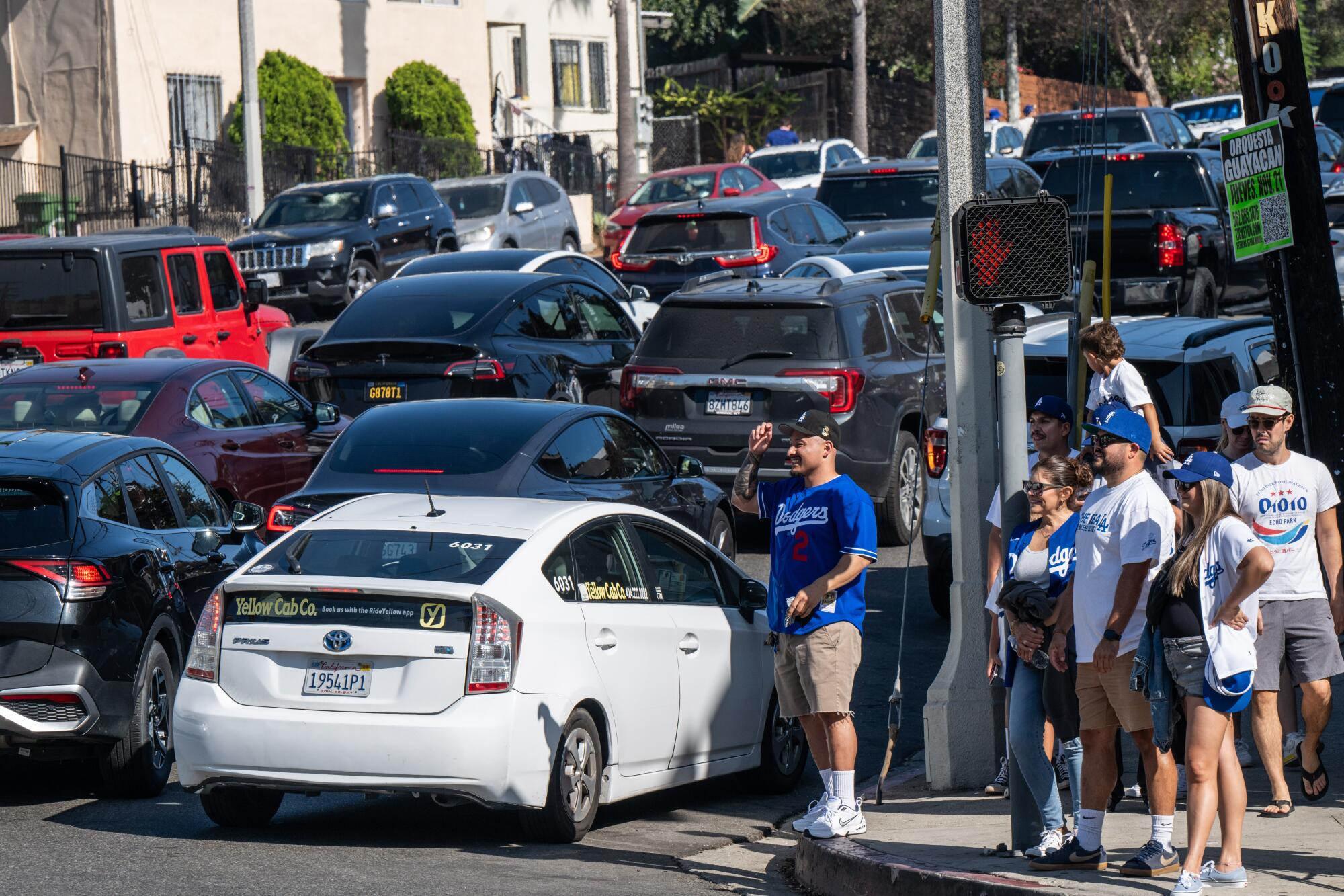 Los Angeles Dodgers fan walk alongside a road packed with vehicle traffic. 