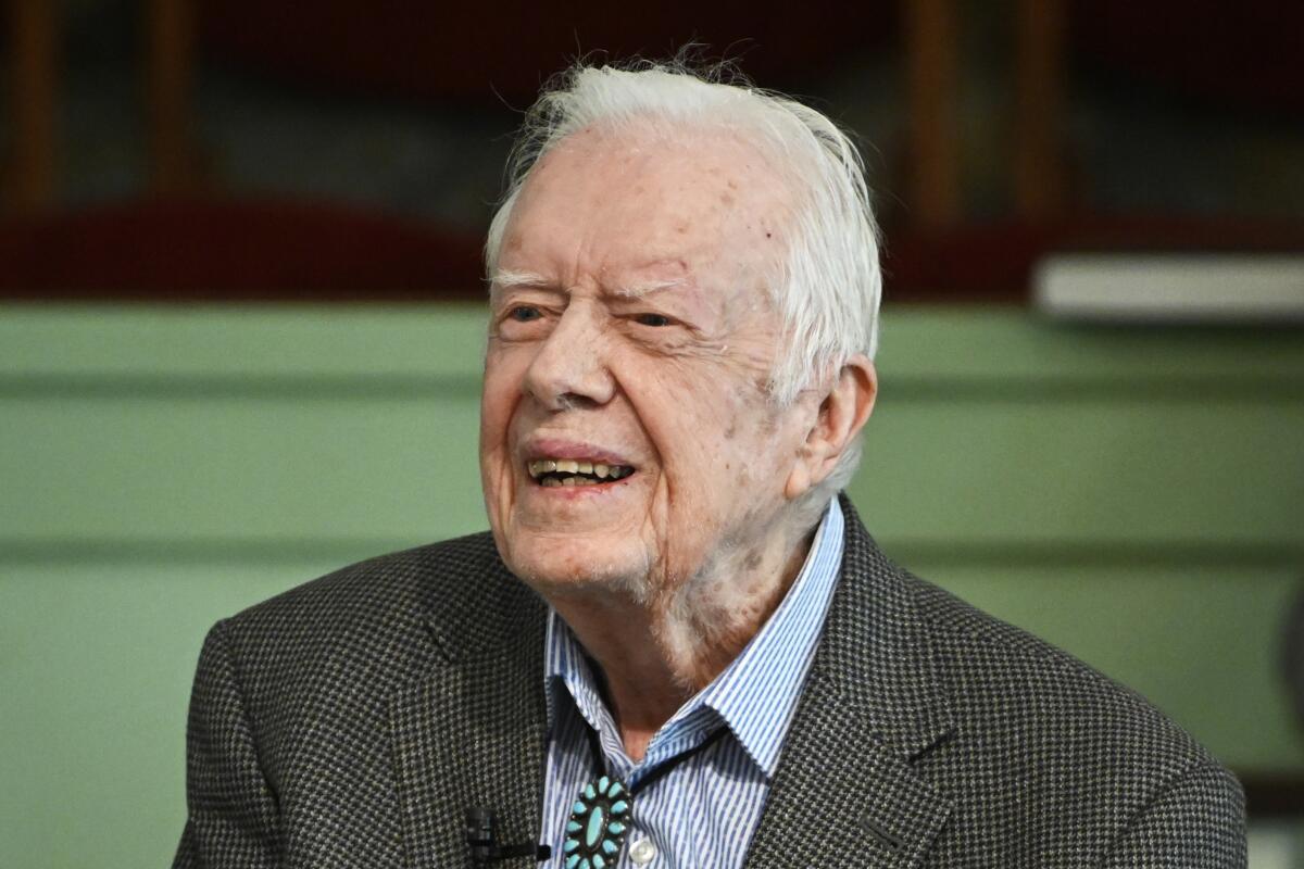 Former President Jimmy Carter smiling in a suit and bolo tie