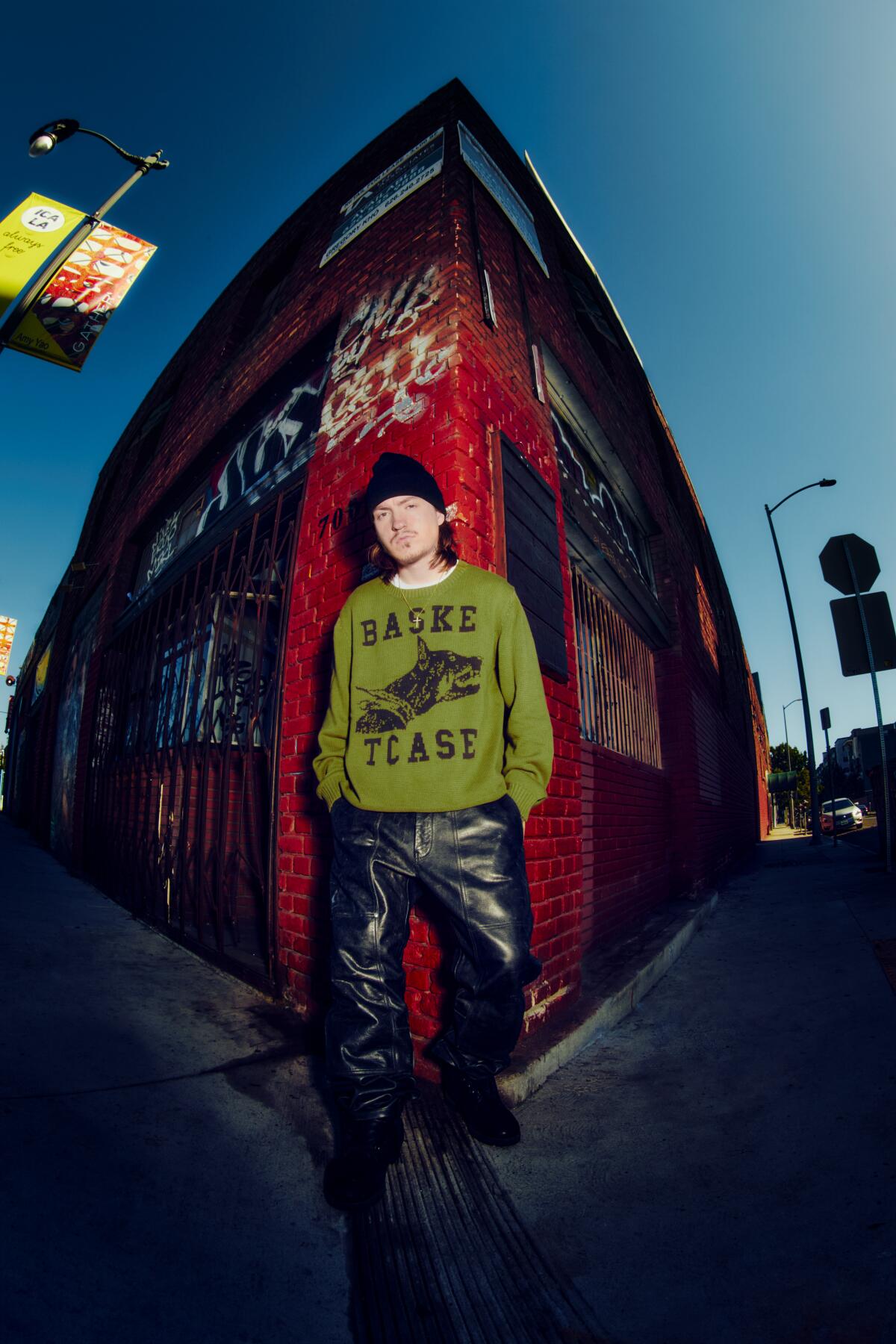 Tommy Richman stands on a corner in front of a building.