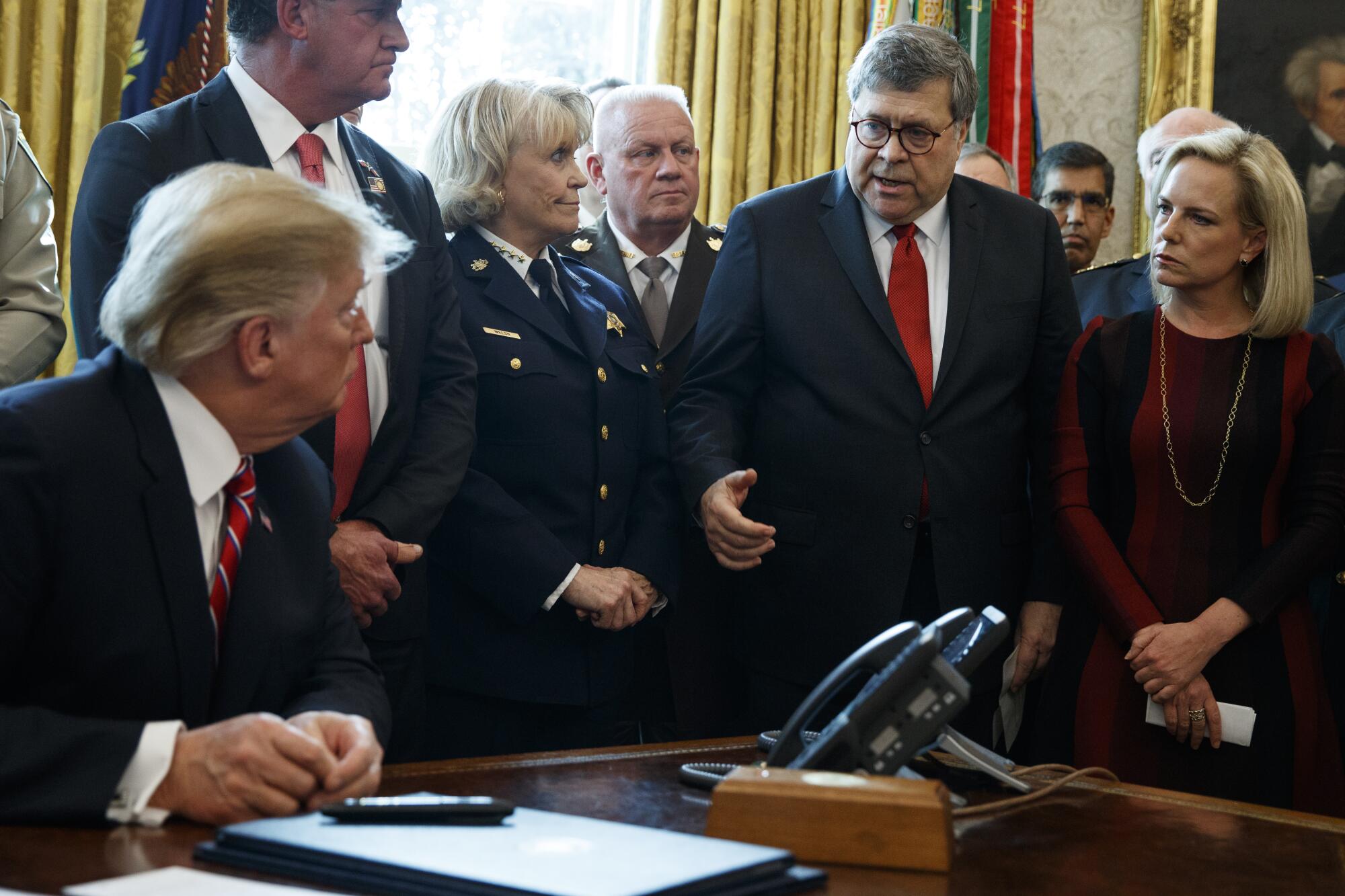 Then-Atty. Gen. Bill Barr speaks to then-President Trump as Trump vetoes a bill in 2019.