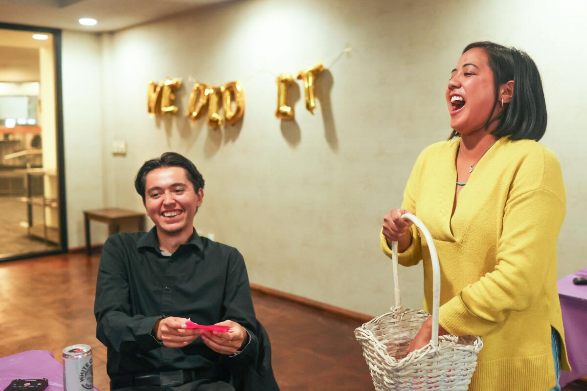 Then-L.A. City Council District 14 candidate Ysabel Jurado reaches into a basket to draw a name next to a man seated.