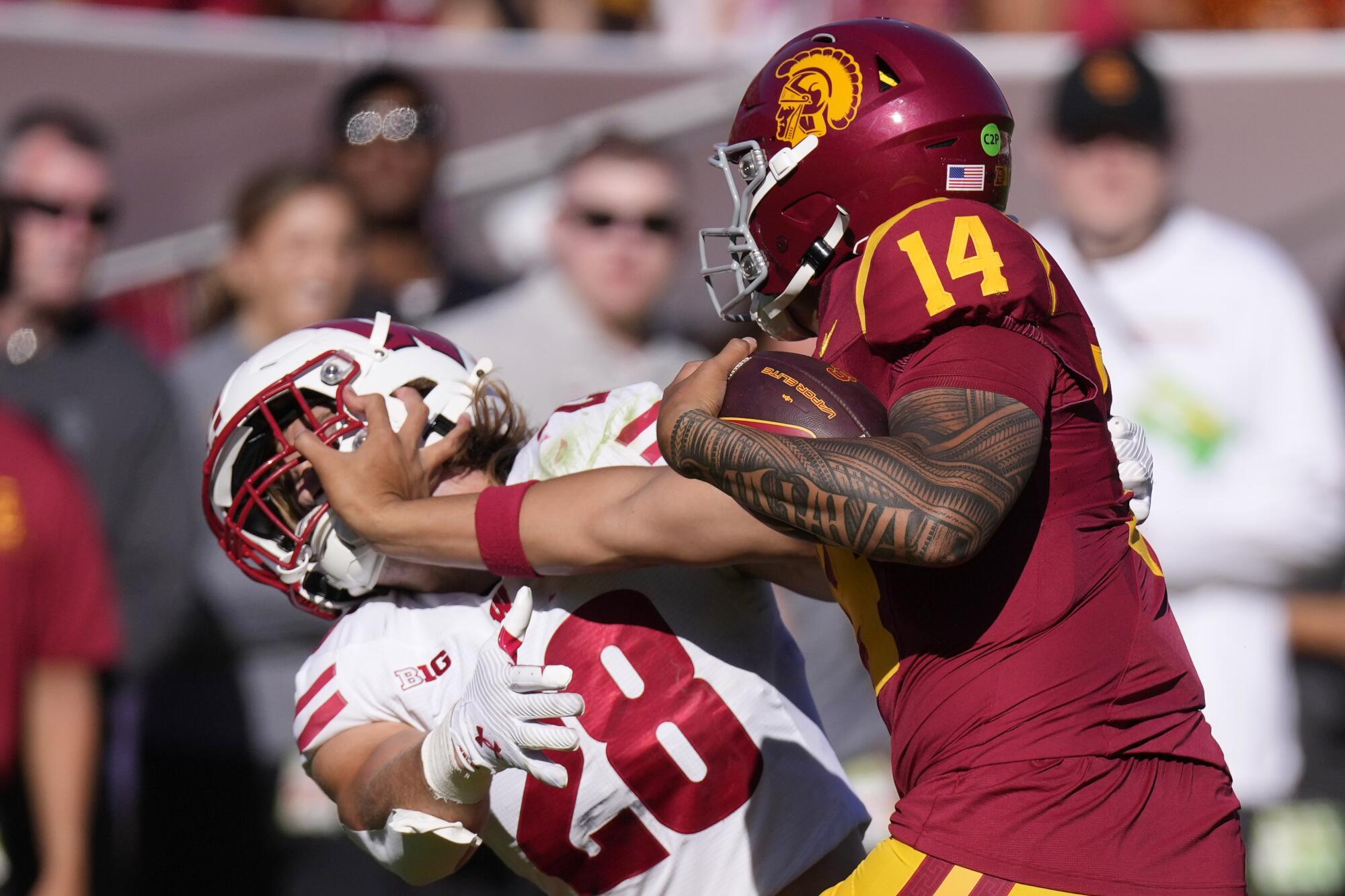 USC quarterback Jayden Maiava fends off Wisconsin linebacker Christian Alliegro as he runs with the ball 