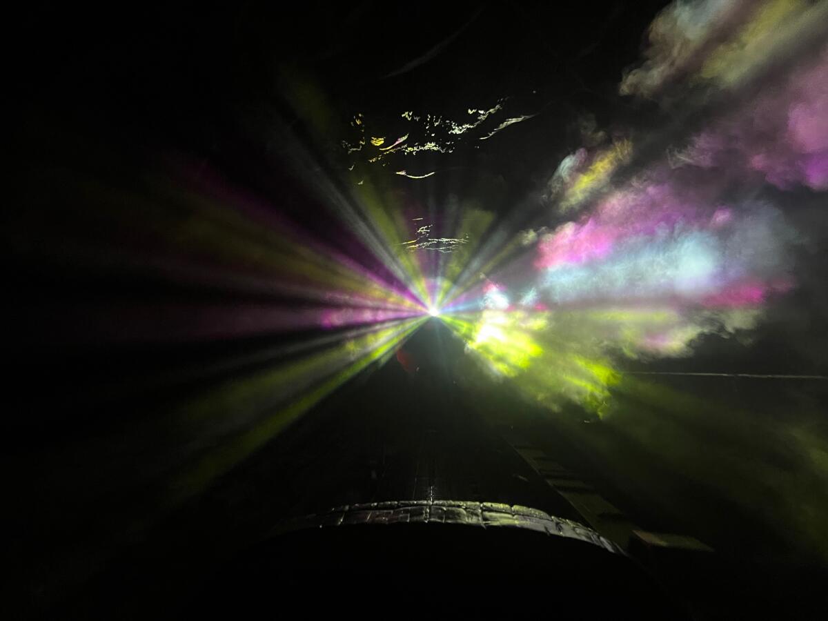 A log vehicle surrounded by rainbow-hued lights. 