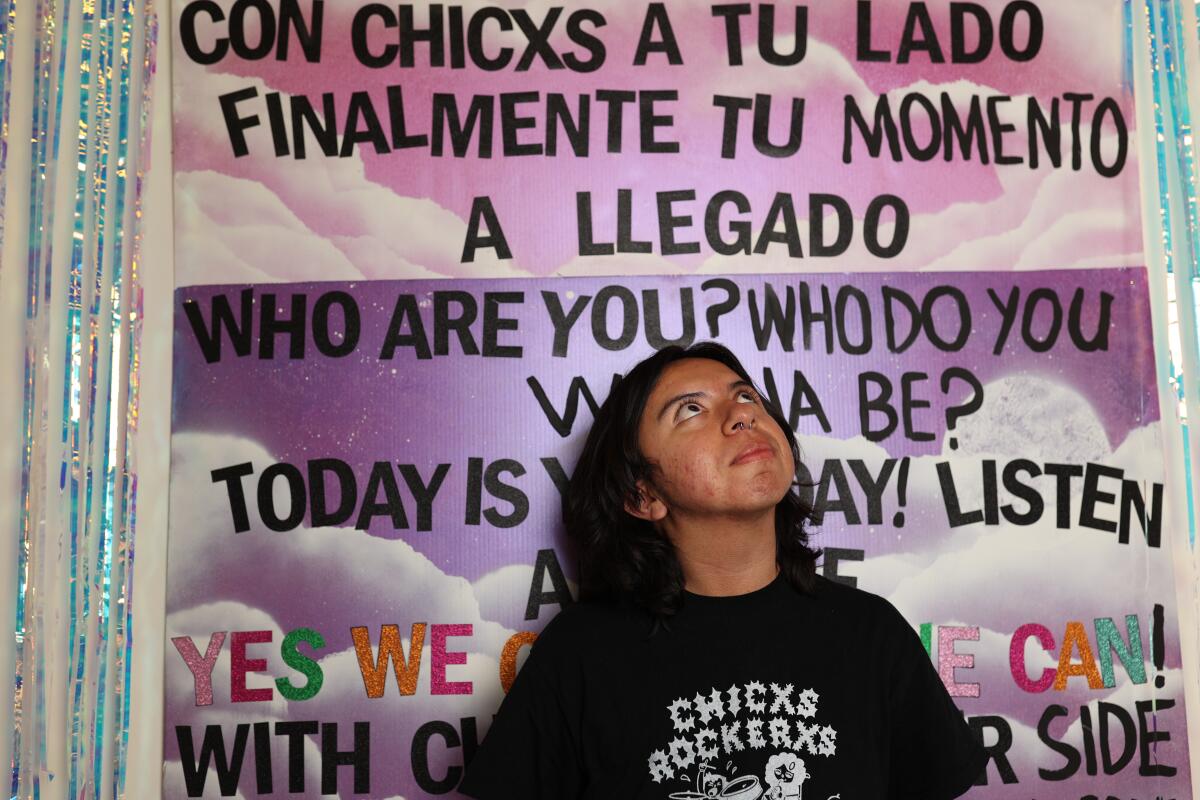 Miles Recio poses for a portrait with Chicxs Rockerxs memorabilia in the background at South Gate Museum 