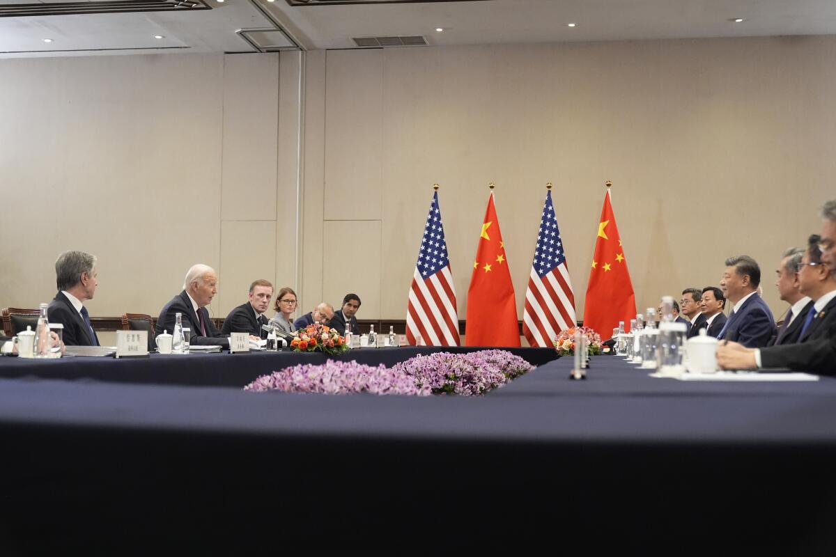 People sit far across from each other along two long rectangular tables. 