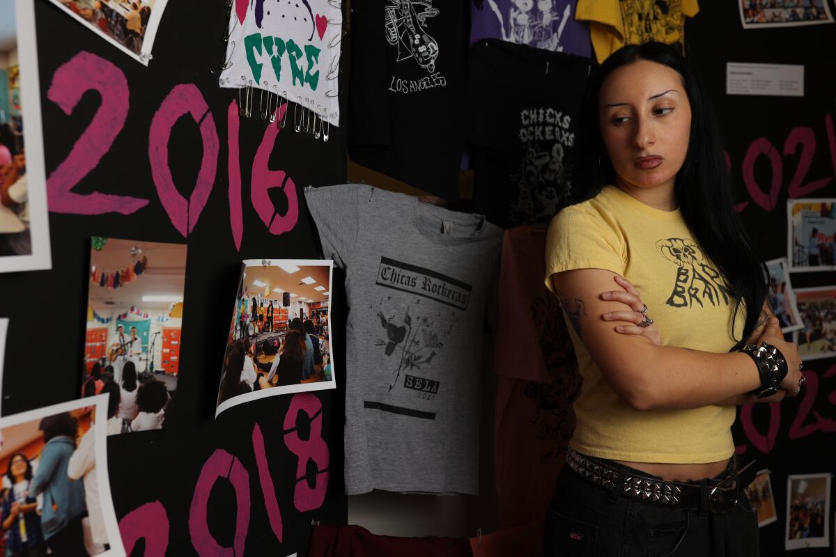 Priscilla Hernandez poses for a portrait with Chicxs Rockerxs memorabilia in the background at South Gate Museum.