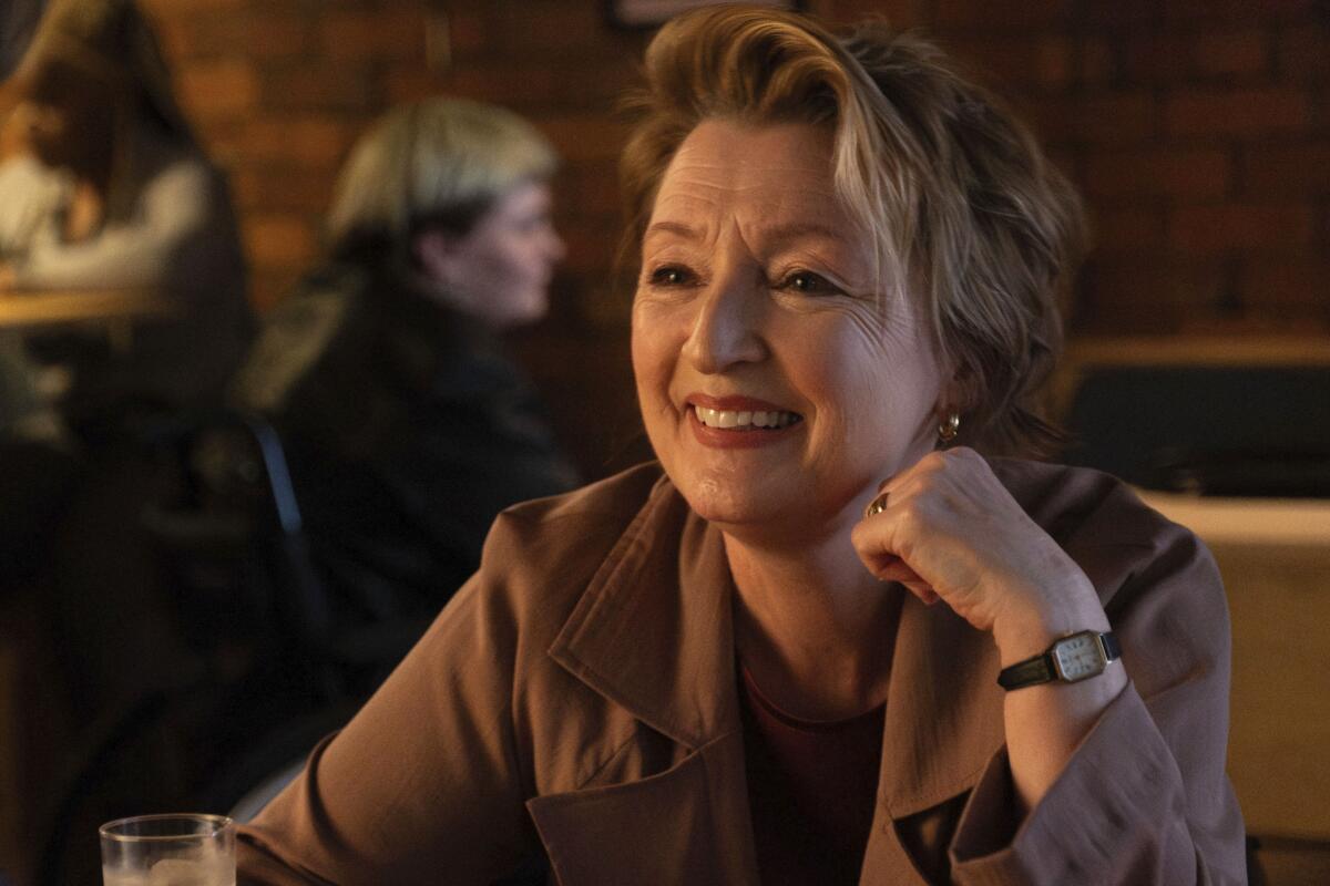 A smiling woman in a brown blouse