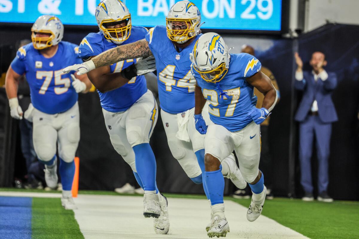 J.K. Dobbins (27) is chased by happy Chargers after the running back's deciding touchdown run against the Bengals. 