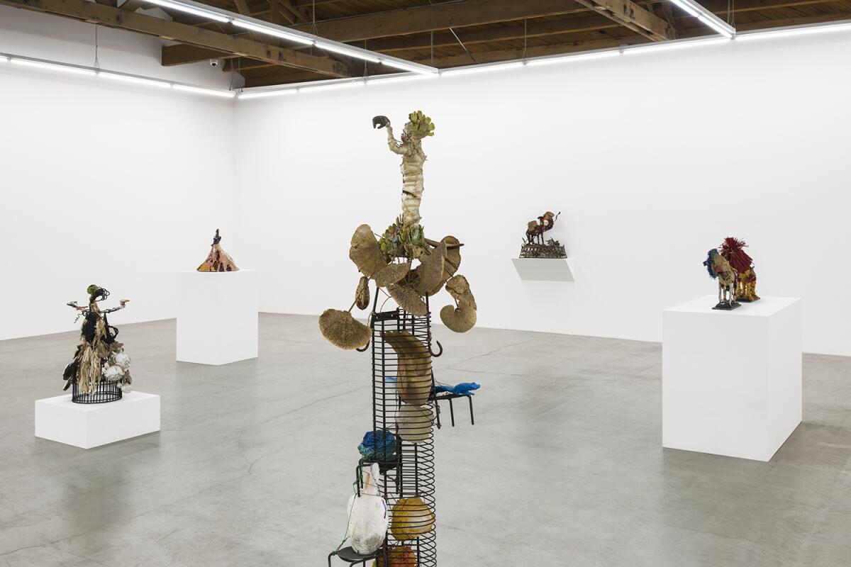 Sculptures on white cube-shaped pedestals of various heights in a white-walled art gallery