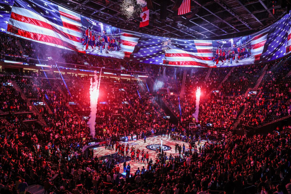 Players and fans stand for the national anthem before Monday's game between the Clippers and Golden State Warriors.