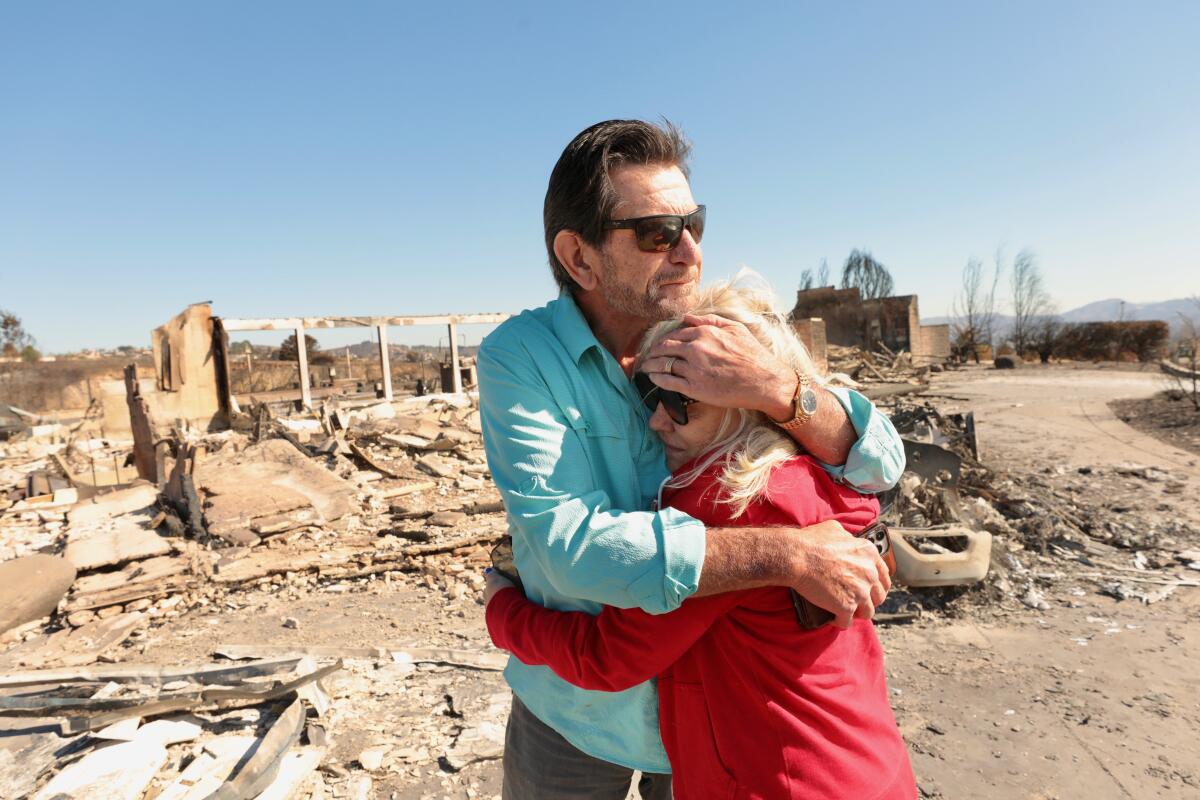 Stanley Jensen hugs his wife, Dawn DaMart, after surveying the ruins of their home in Camarillo.