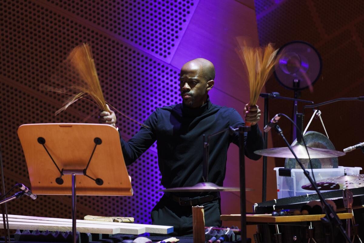 A percussionist performs backed by a purple spotlight.