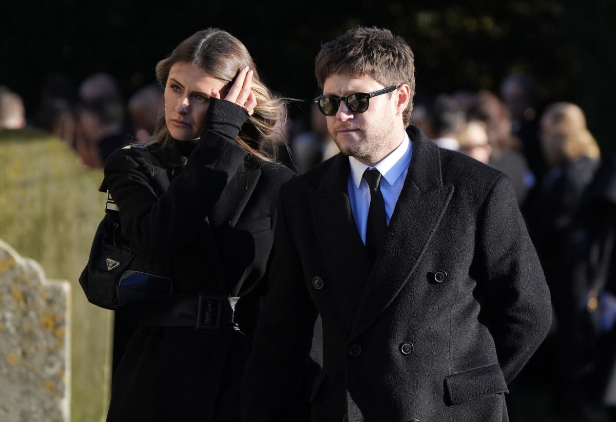 A woman and a man walk together in funeral attire