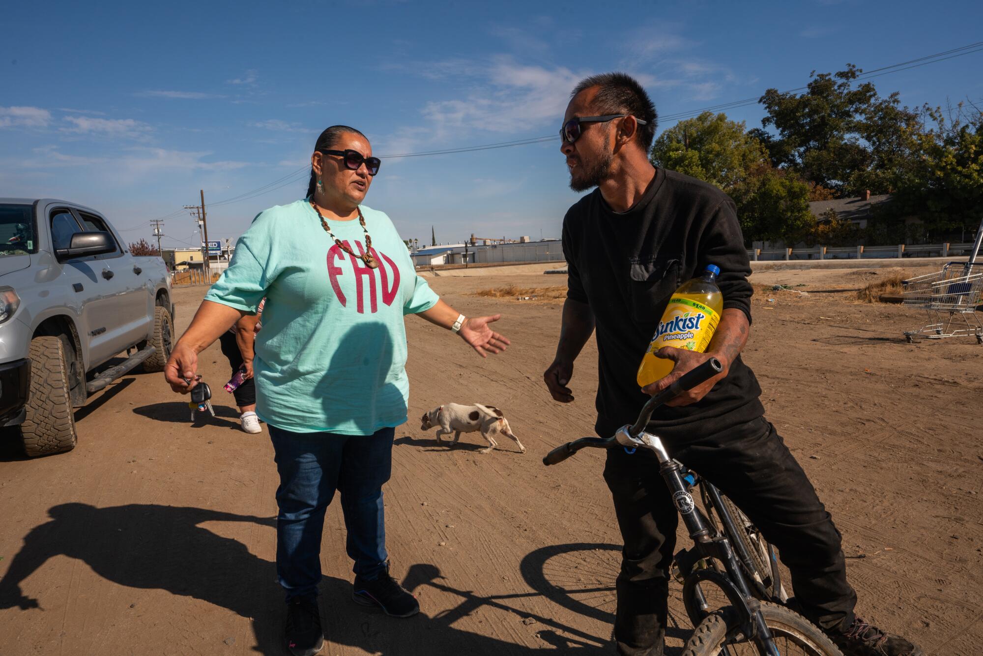 Homeless advocate Dez Martinez converses with a man on a bike