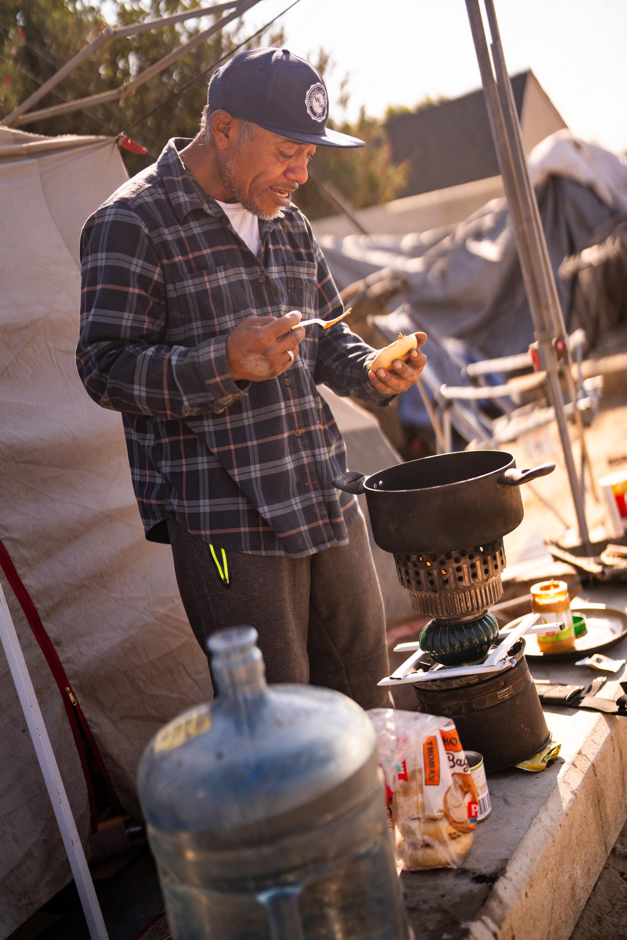 Erick Lopez prepares a bagel with peanut butter at a homeless encampment in Fresno.