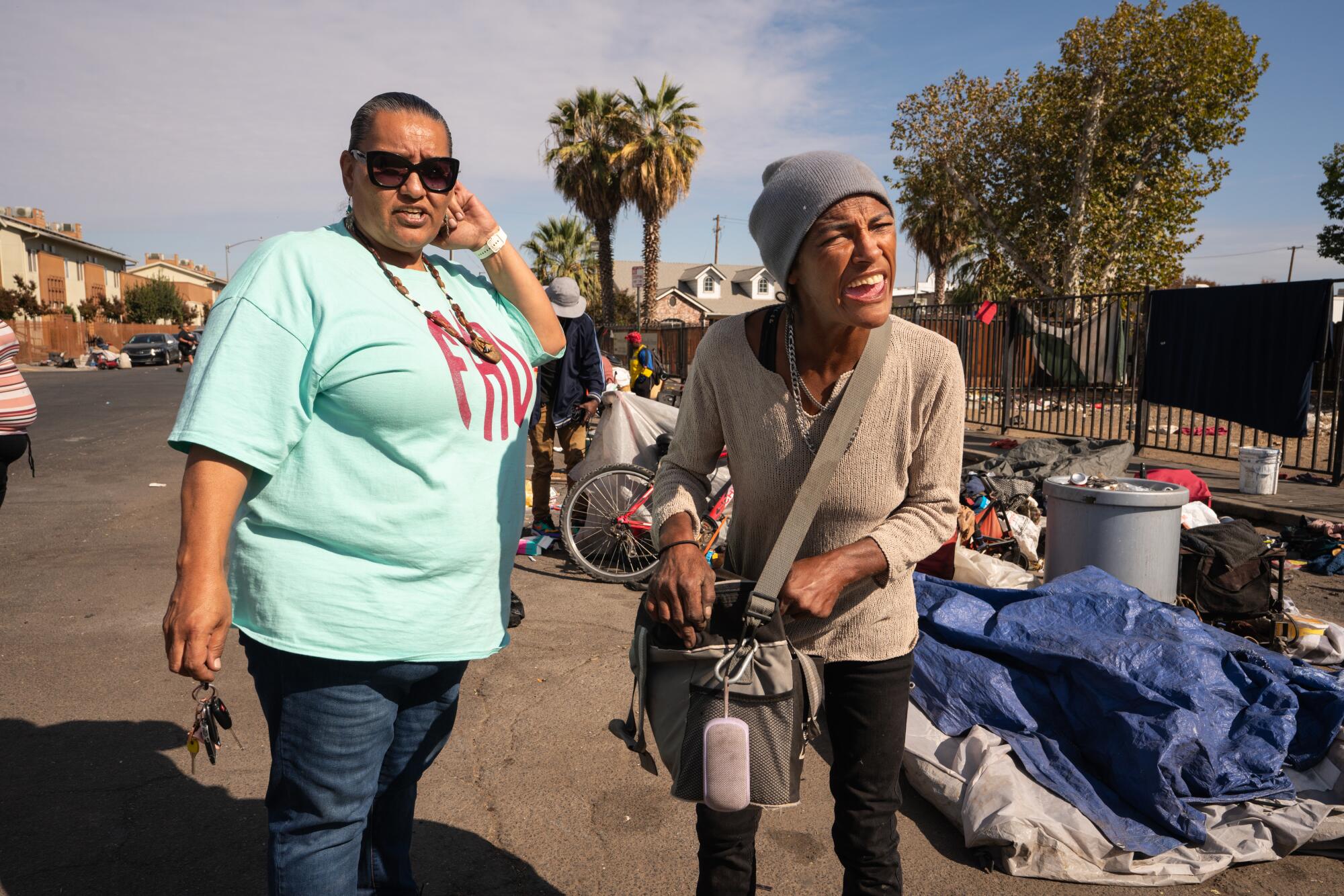 Homeless advocate Dez Martinez talks with a woman in a crowded homeless encampment in Fresno.