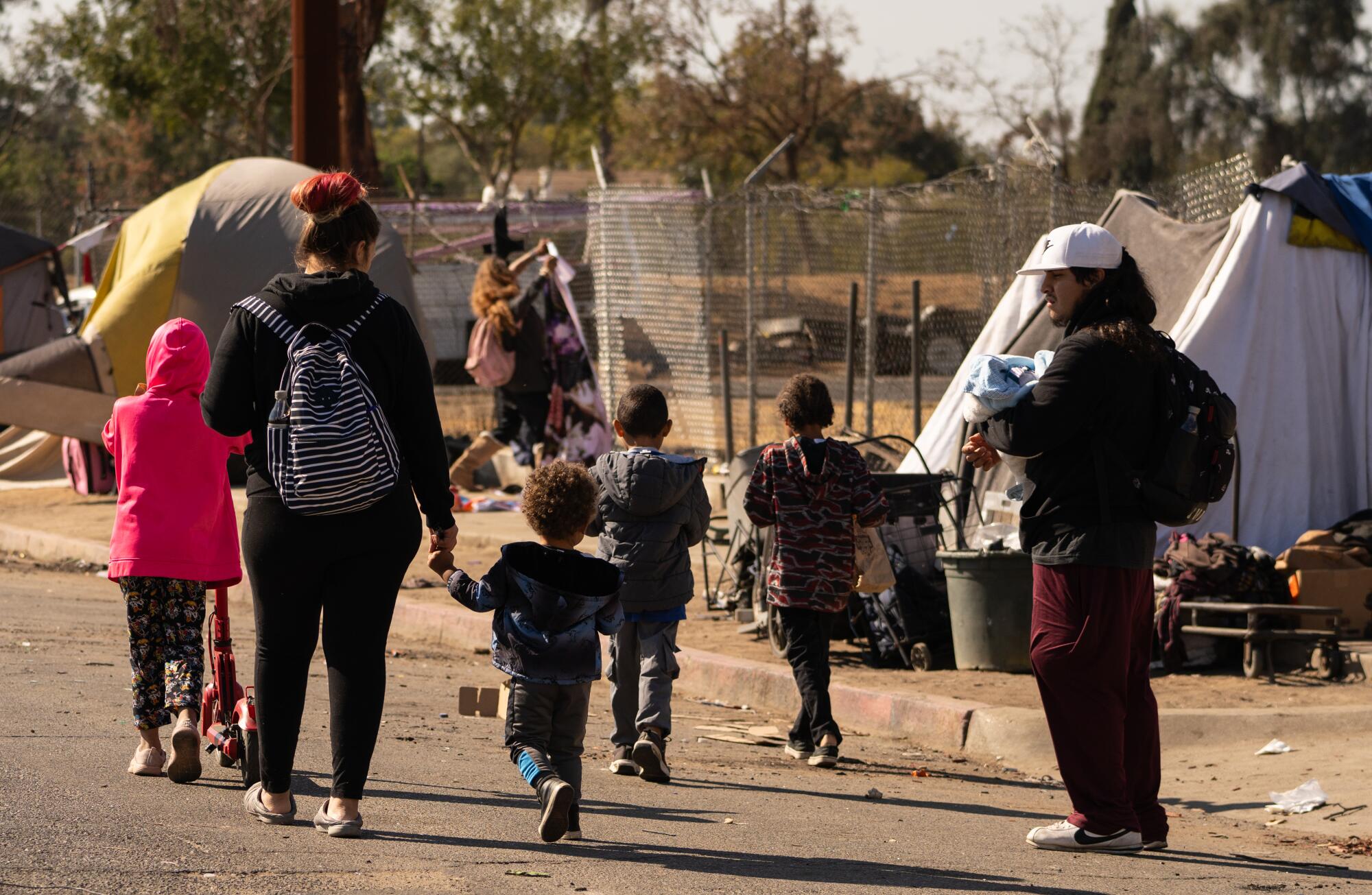 A family walks past tents and tarps on Santa Clara Street in downtown Fresno.