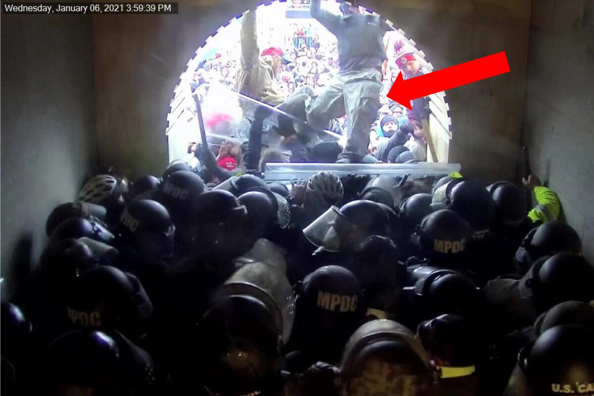 An image with a red arrow pointing to a man stepping on a crowd of helmeted officers in a tunnel