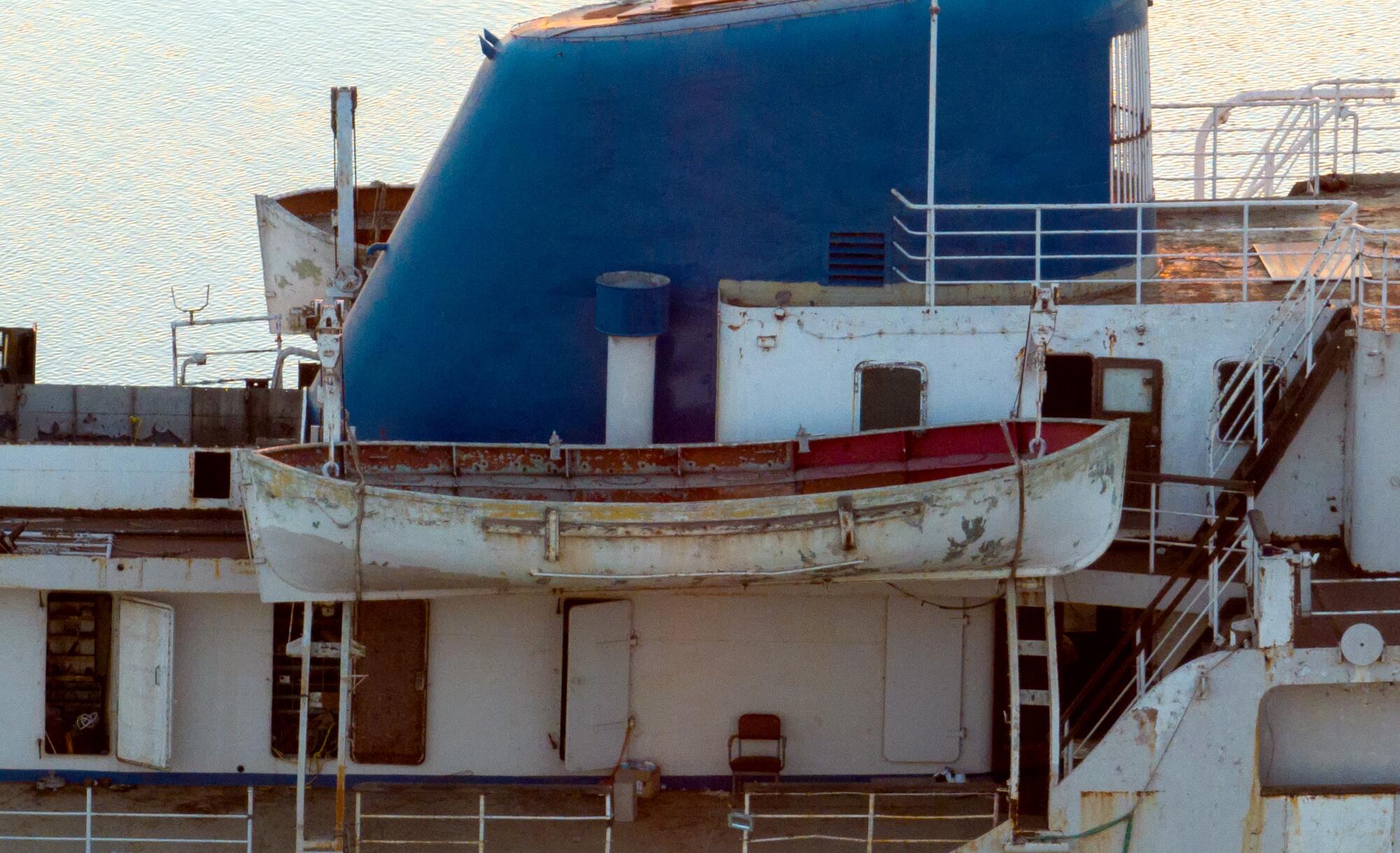 A decrepit lifeboat hangs from the upper deck of the Aurora.