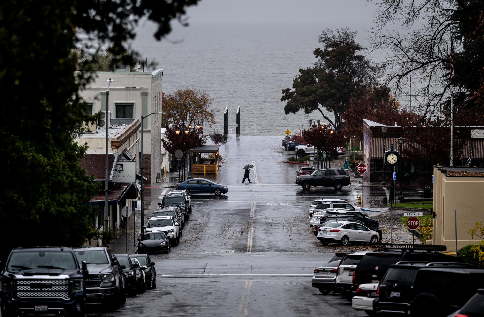 The view down a wet city street ending at a lake