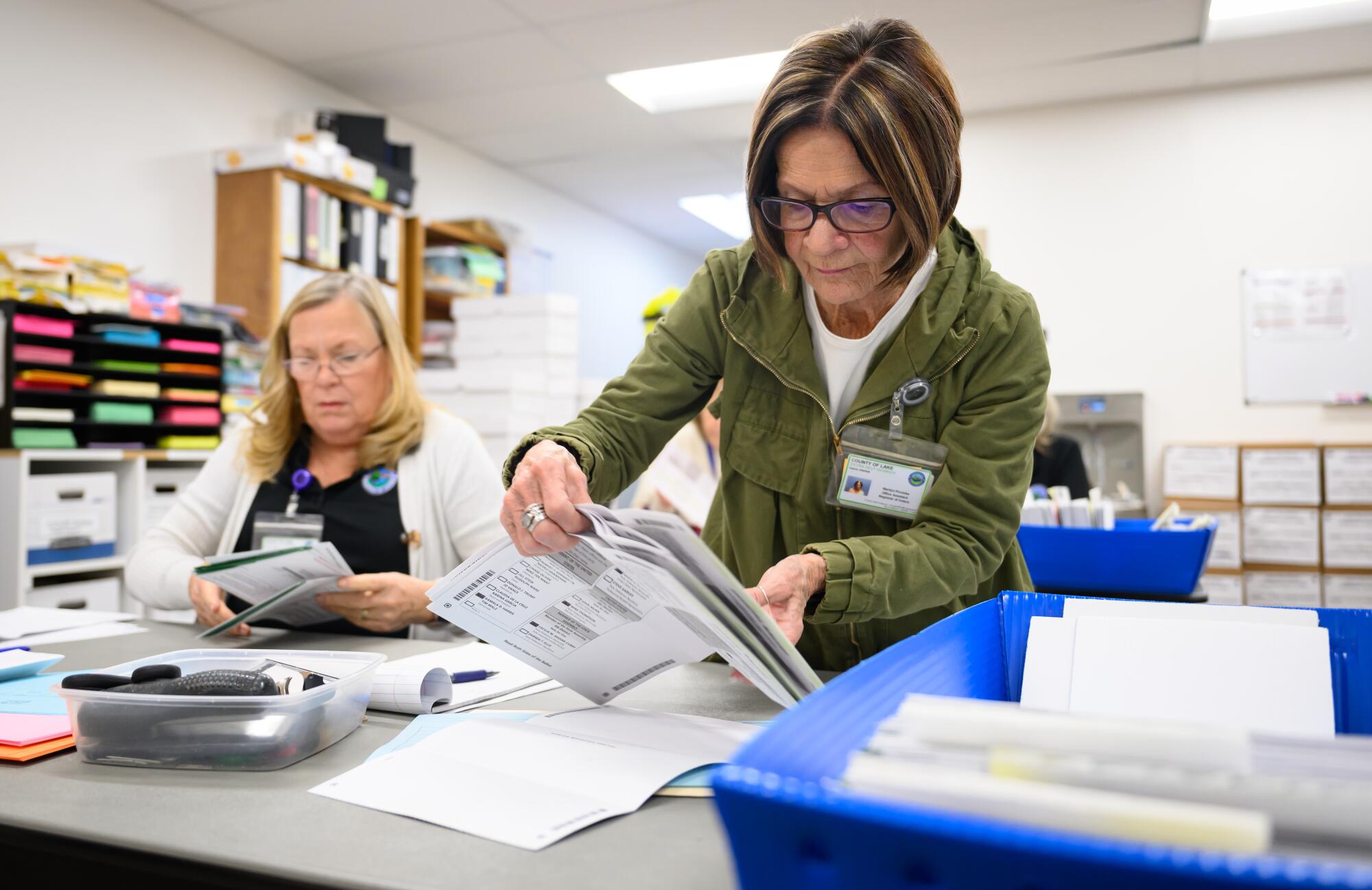 Two women handle ballots at a table