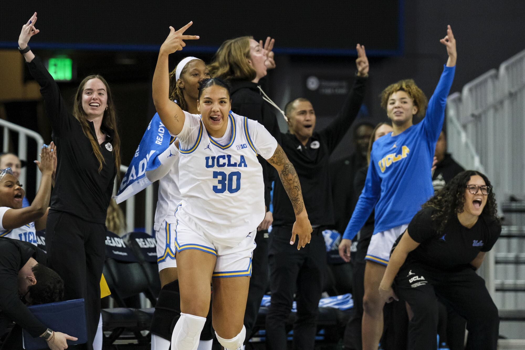 UCLA forward Timea Gardiner shouts after making a three pointer against Arkansas while teammates cheer from the bench