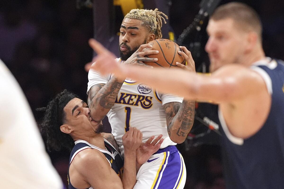 Denver Nuggets guard Julian Strawther, left, is hit in the face by Los Angeles Lakers guard D'Angelo Russell.