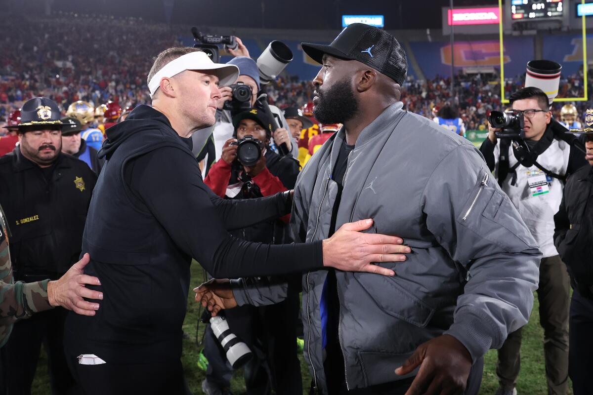 USC coach Lincoln Riley, left, and UCLA coach DeShaun Foster meet on the field after the game.